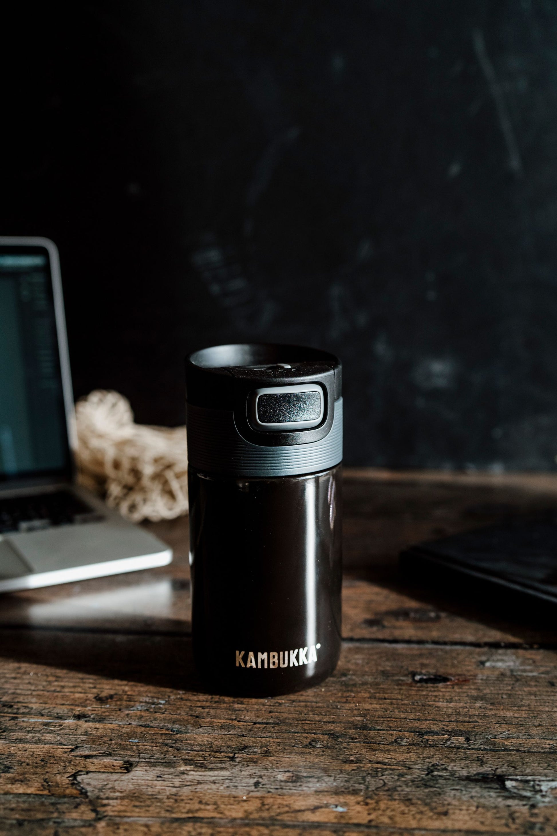 Kambukka Etna 300 ml Pitch Black travel mug standing on a wooden table