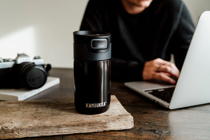 Kambukka Etna 300 ml Pitch Black travel mug standing on a wooden table